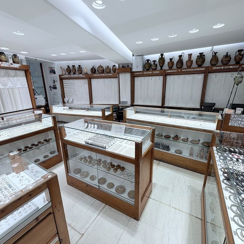 Inside the shop: the glass cases and the wall of chains, with the amphorae above